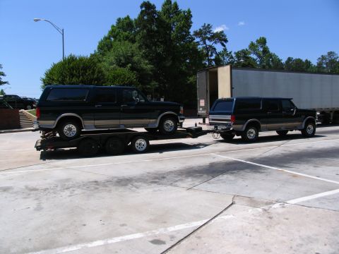 1995 Ford C-350 (Centurion Conversions) - Two Ford Broncos are shown, with one loaded onto a trailer and being towed by the second vehicle.