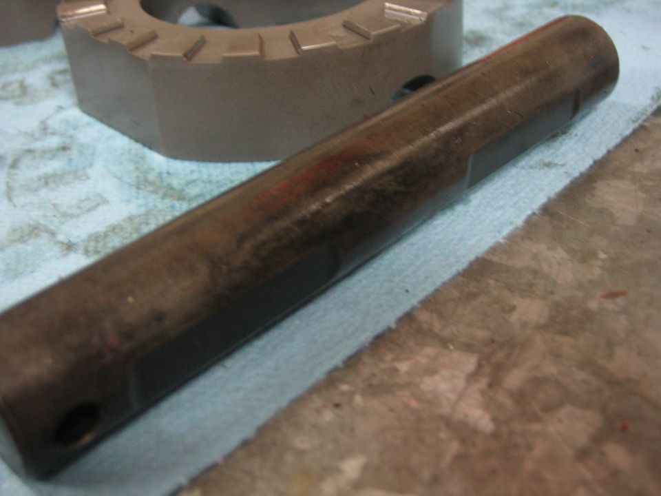 Metal shaft with hexagonal sections and a toothed gear on a blue shop towel
