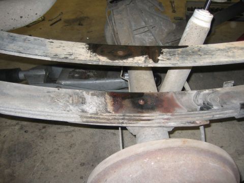 1996 Ford Bronco - Close-up view of the rear leaf springs and shock absorber, showing signs of fluid leakage.