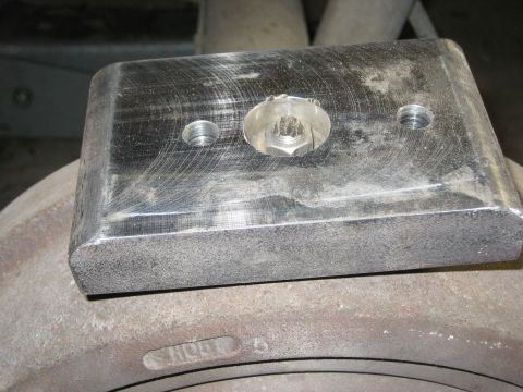 1996 Ford Bronco - Close-up of a metal bracket with a bolt and screw holes positioned on a brake rotor.