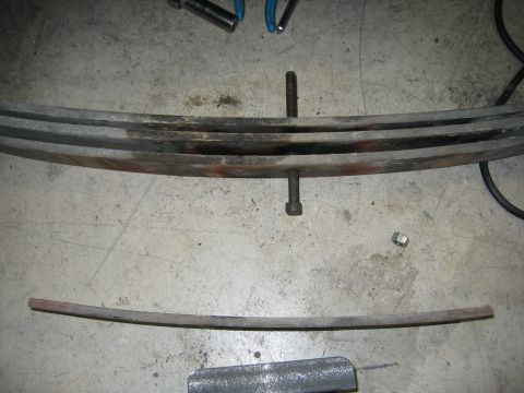 1996 Ford Bronco - Leaf springs and hardware are laid out on a concrete surface, possibly for repair or replacement.