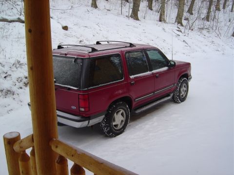 1986 Ford Bronco - Maroon SUV parked in a snowy landscape, viewed from a wooden porch railing.