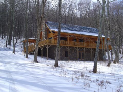 1986 Ford Bronco - A wooden cabin sits on a hill surrounded by bare trees and snow.