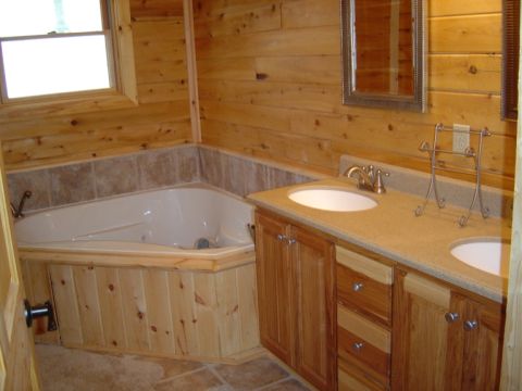 1986 Ford Bronco - This bathroom features a corner jacuzzi tub and a double sink vanity, all surrounded by warm wood paneling.