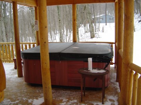 1986 Ford Bronco - A hot tub sits on a covered wooden deck during a snowy day, with a house visible in the distance.