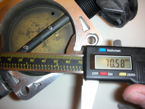 1998 Ford Crown Victoria - digital caliper reads 70.58 mm while measuring the bore of a metal throttle-body part alongside a steel ruler.
