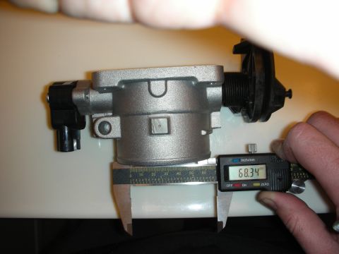1998 Ford Crown Victoria - silver aluminum throttle body rests on a ruler as a digital caliper shows a 68.34 mm reading.