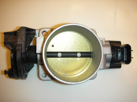 1998 Ford Crown Victoria - large aluminum twin-bore throttle body with its butterfly blades visible lies on a light surface.