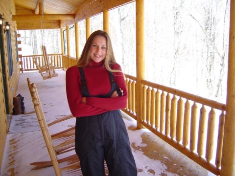 1986 Ford Bronco - A woman poses on a snow-covered wooden porch of a log cabin.