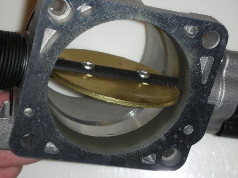 1998 Ford Crown Victoria - throttle body held in hand, showing the open butterfly valve and bolt-hole flange in detail.