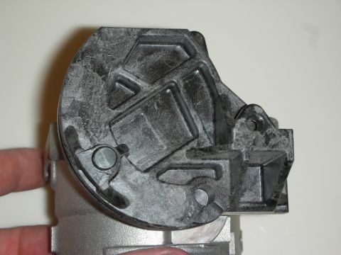 1998 Ford Crown Victoria - Close-up of the dark plastic gear-cover side of a throttle body assembly held in hand.