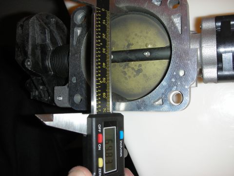 1998 Ford Crown Victoria - throttle body bore being measured with a digital caliper, the display reading visible at the bottom.