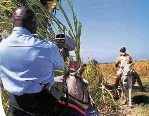 1996 Ford Probe - A man uses a radar gun in a rural setting, with a donkey and rider in the background.