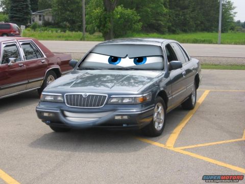 1985 Mercury Grand Marquis - A Mercury Grand Marquis is parked in a lot, with cartoon eyes and a smile superimposed on its front.