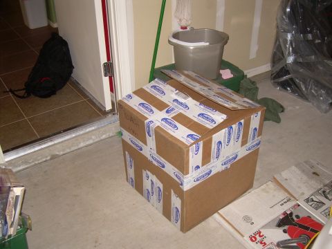 1996 Ford Probe - A taped cardboard box sits on a garage floor near a doorway, with a bucket and mop in the background.