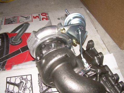 1996 Ford Probe - A turbocharger assembly is shown, likely for an automotive engine, with some packaging in the background.