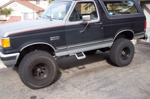 1990 Ford Bronco - This Ford Bronco features a two-tone paint scheme and aftermarket side steps, suggesting a custom build.