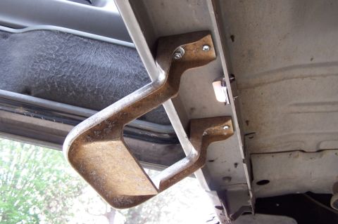 1990 Ford Bronco - A close-up view of a vehicle's running board bracket, showing signs of rust and wear.