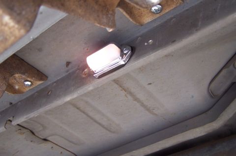 1990 Ford Bronco - Close-up of an underbody light fixture mounted to a vehicle's frame.