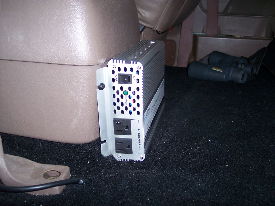 Power inverter and binoculars on carpeted floor inside a vehicle