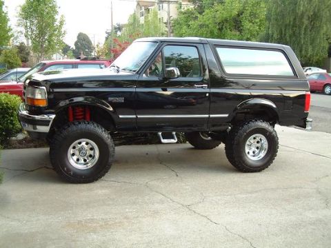 1996 Ford Bronco - Side view of a black 1996 Ford Bronco, modified with a lift kit and large tires.