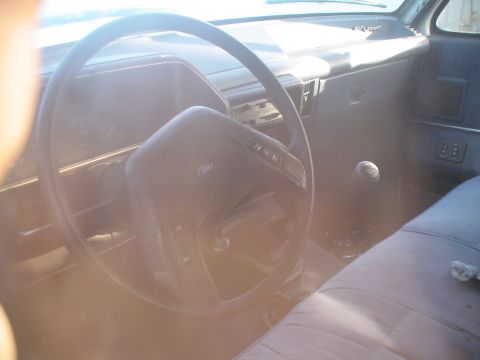 1993 Ford C-350 (Centurion Conversions) - The interior of a truck shows the steering wheel, dashboard, and a bench seat with a visible gear shift lever.