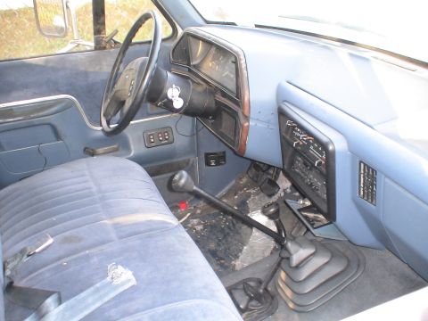 1993 Ford C-350 (Centurion Conversions) - Interior view of a truck's dashboard and seating area, showing the steering wheel and gear shifts.