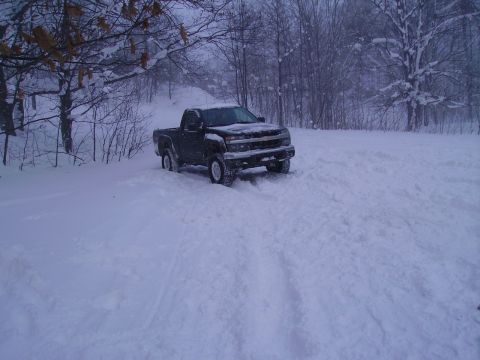 2000 Chevrolet Tahoe - A dark pickup truck navigates through a snow-covered landscape, likely during a winter storm.