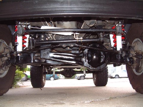 1996 Ford Bronco - The front suspension and differential of a 4x4 vehicle are shown, with other vehicles in the background.