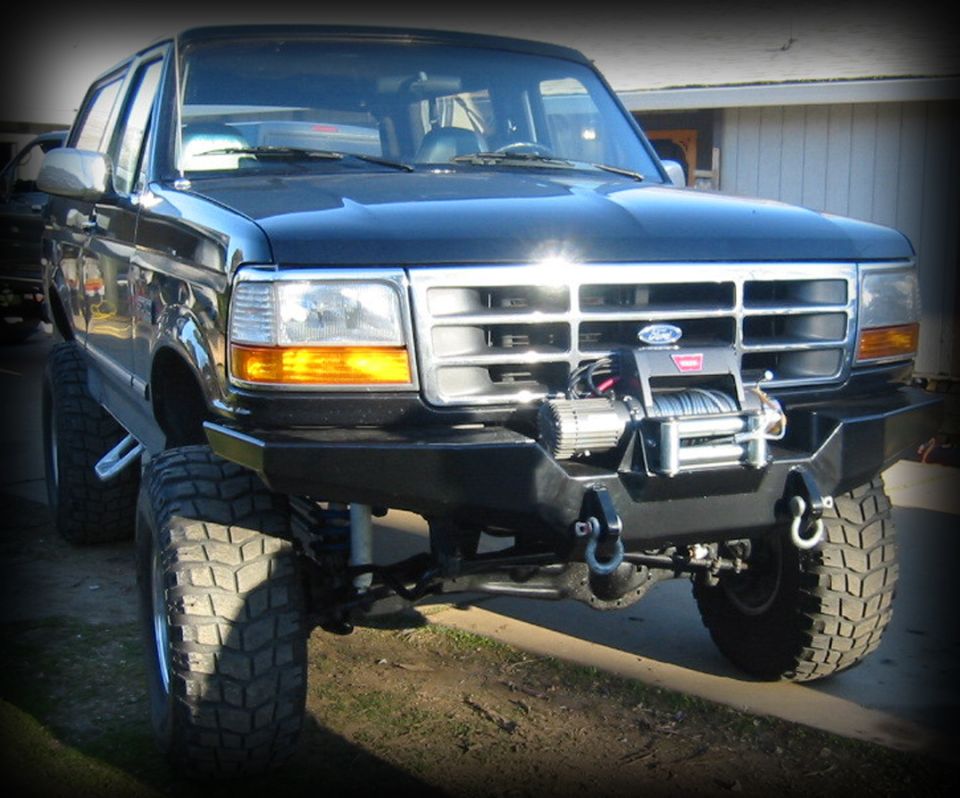 Black lifted Ford SUV, front 3/4 view, steel bumper with winch, big off-road tires