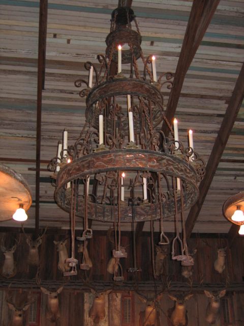 1996 Ford Bronco - Rustic chandelier with candle lights and cattle brands hangs above taxidermied deer heads.