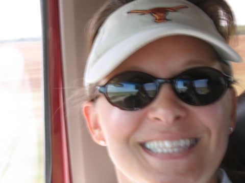 1996 Ford Bronco - A woman smiles while wearing sunglasses and a visor with the Texas Longhorns logo, seen from inside a vehicle.