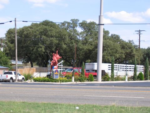 1996 Ford Bronco - A roadside scene with a cowboy statue, a white pickup, a red truck, and a white trailer.