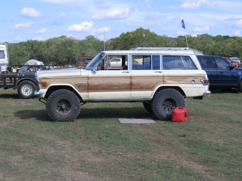 1996 Ford Bronco - A lifted station wagon with wood paneling sits on a grassy field next to other vehicles.