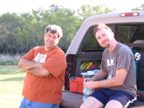 1996 Ford Bronco - Two men relax in the open tailgate of a pickup truck, surrounded by outdoor gear.