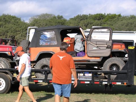 1996 Ford Bronco - Two men stand near an orange Jeep Wrangler loaded onto a trailer, with another Jeep to its left.