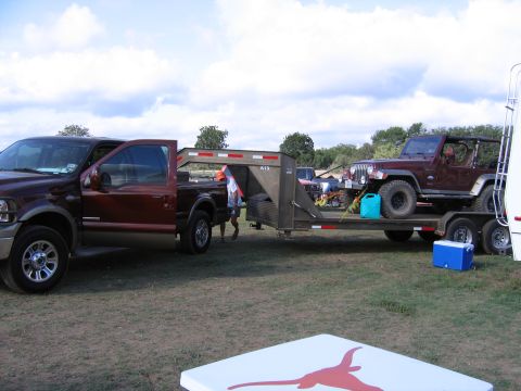 1996 Ford Bronco - A Ford F-Series truck is parked next to a trailer carrying a Jeep Wrangler under a cloudy sky.