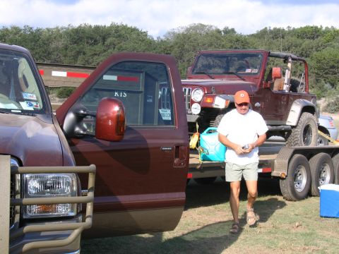 1996 Ford Bronco - A man walks past a Ford F-250 Super Duty truck and a Jeep Wrangler on a trailer.