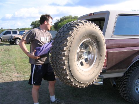 1996 Ford Bronco - A man stands next to a 1996 Ford Bronco, holding a purple bag, with a spare tire mounted on the rear.