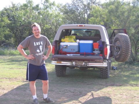 1996 Ford Bronco - A man poses next to his SUV, which is loaded with camping equipment for an outdoor excursion.