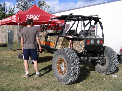 1996 Ford Bronco - This off-road buggy features a camouflage wrap and a prominent roll cage, seen from the rear with large, aggressive tires.