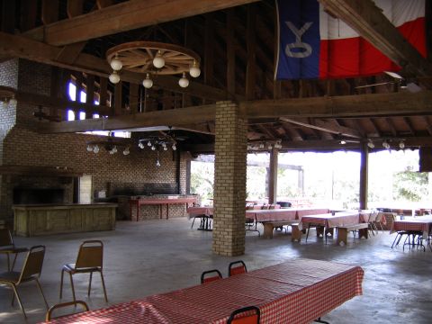 1996 Ford Bronco - A large covered pavilion set up with tables and chairs, a brick fireplace and decorative flags.
