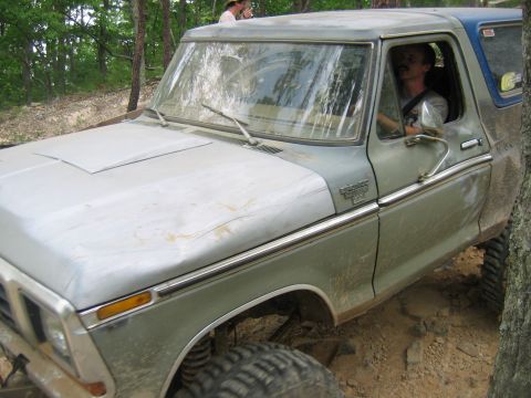 1992 Ford Mustang - A man drives a vintage Ford Bronco off-road, its two-tone paint visible.