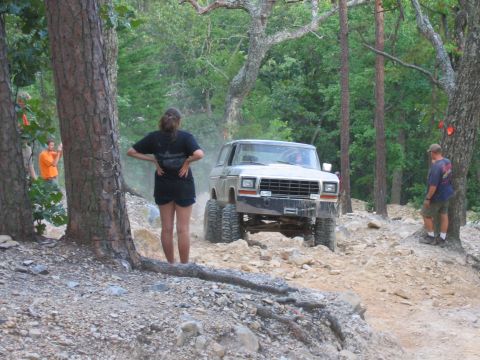 1992 Ford Mustang - This modified SUV is navigating a challenging off-road course with spectators observing the action.