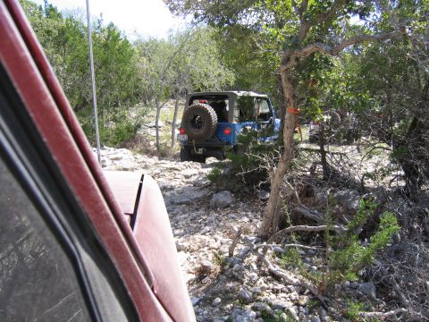 1996 Ford Bronco - A blue Jeep Wrangler navigates a rocky trail, with another vehicle visible in the foreground.