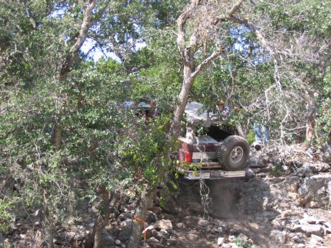 1996 Ford Bronco - Multiple off-road vehicles are seen navigating a challenging, wooded, and rocky trail.