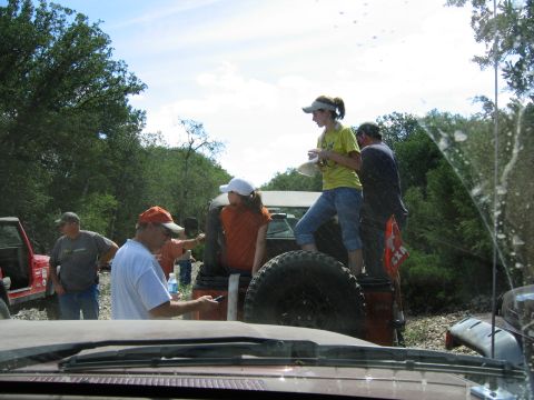1996 Ford Bronco - A group of people are standing around and on several off-road vehicles in a natural setting.