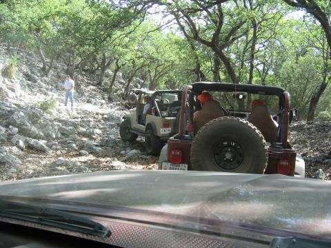 1996 Ford Bronco - Two Jeep Wranglers traverse a challenging, rocky path through a wooded area, with one vehicle in the foreground and another following behin…