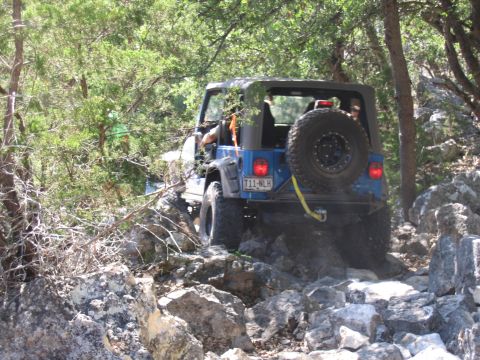 1996 Ford Bronco - Jeep Wrangler tackling a difficult rocky off-road path with another vehicle following.