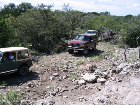 1996 Ford Bronco - A red 1996 Ford Bronco navigates a rocky trail with another vehicle visible behind it.